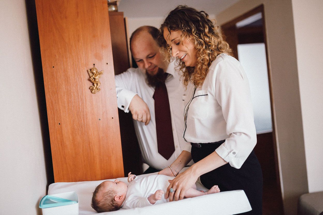 Fotograf na chrzciny rodzice ubierają dziecko na chrzest