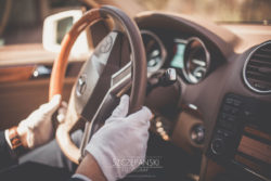 Detale ślubne dłonie szofera ślubnego w rękawiczkach ułożone na kierownicy