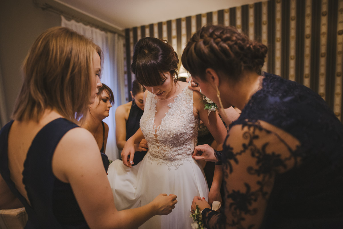 Druhny poprawiają suknię ślubną pannie młodej w hotelu Dwór Korona Karkonoszy.