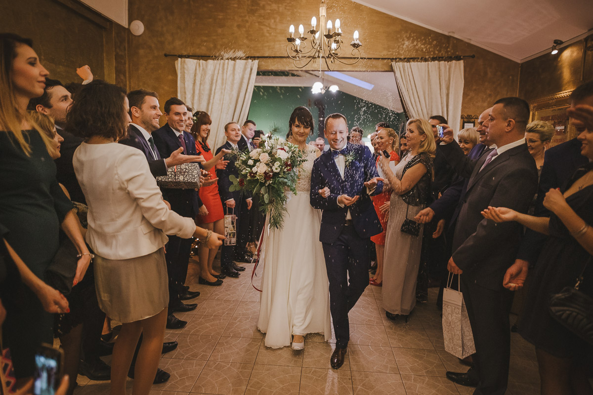 Nowożeńcy wychodzą wśród gości z sali po zakończonej ceremonii zaślubin w hotelu Dwór Korona Karkonoszy.