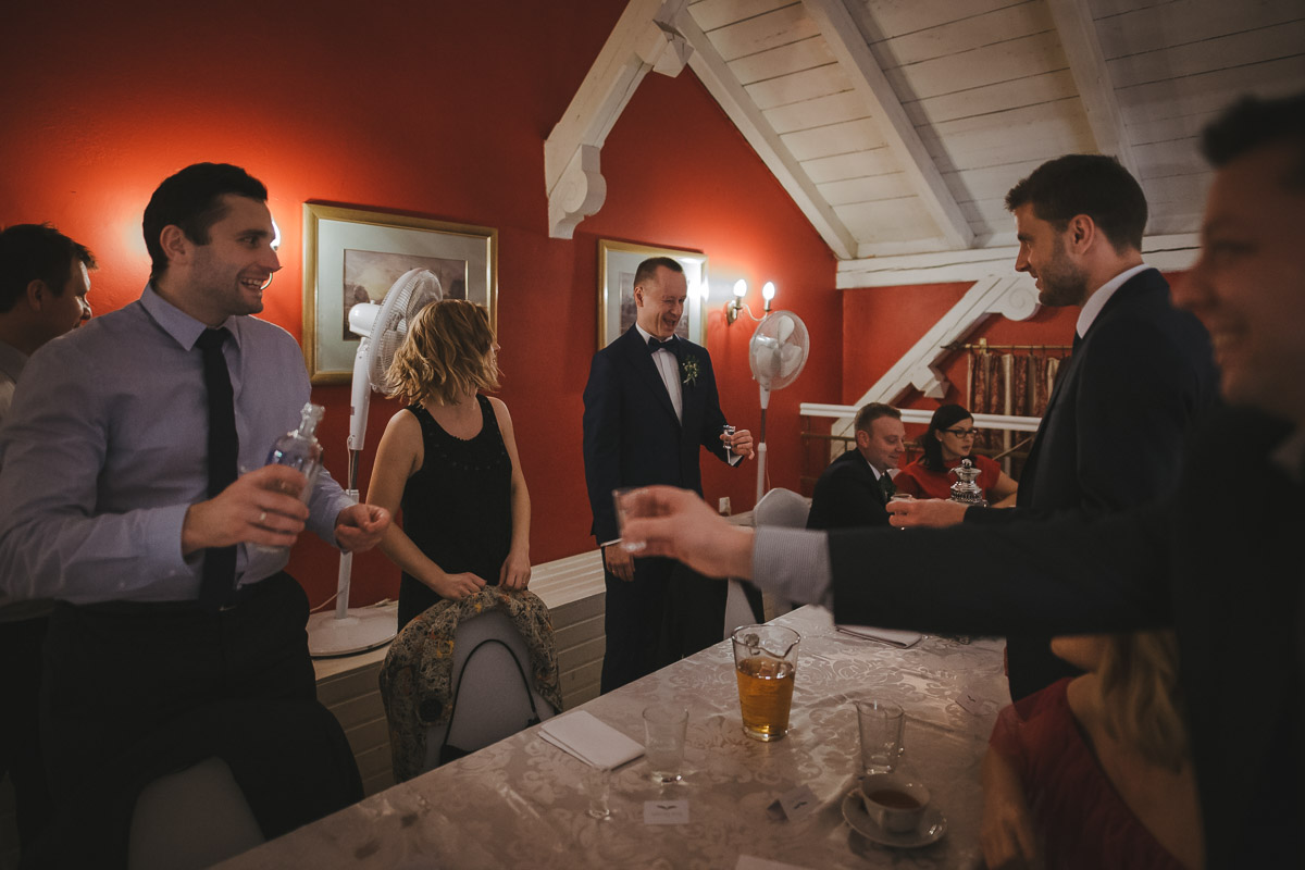 Pan młody i goście przy stoliku piją alkohol podczas przyjęcia weselnego w hotelu Dwór Korona Karkonoszy.