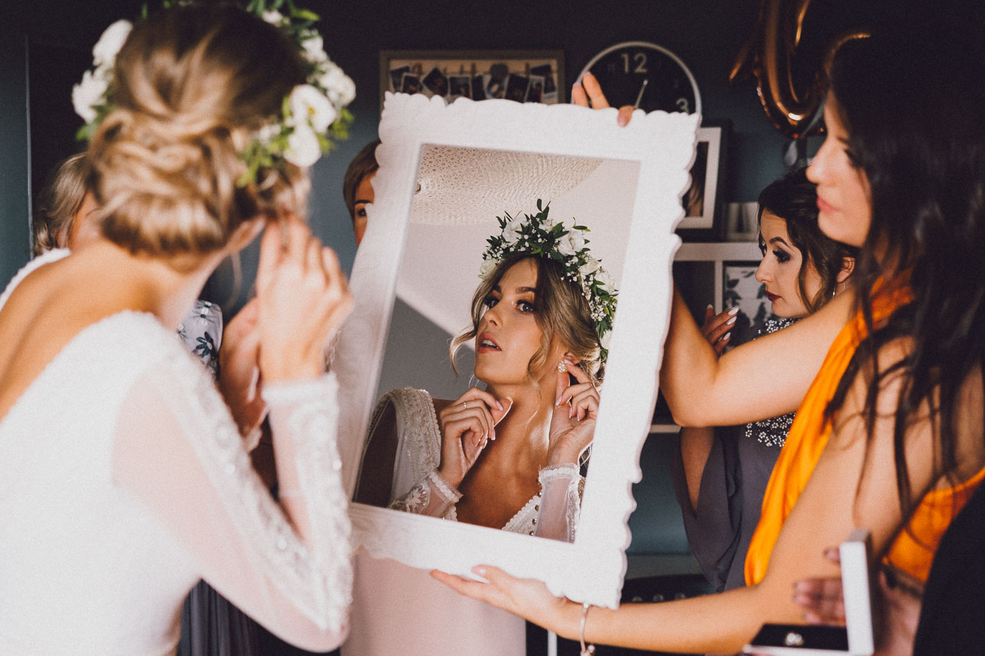 Panna Młoda na przygotowaniach ślubnych zakłada kolczyk przeglądając się w lustrze