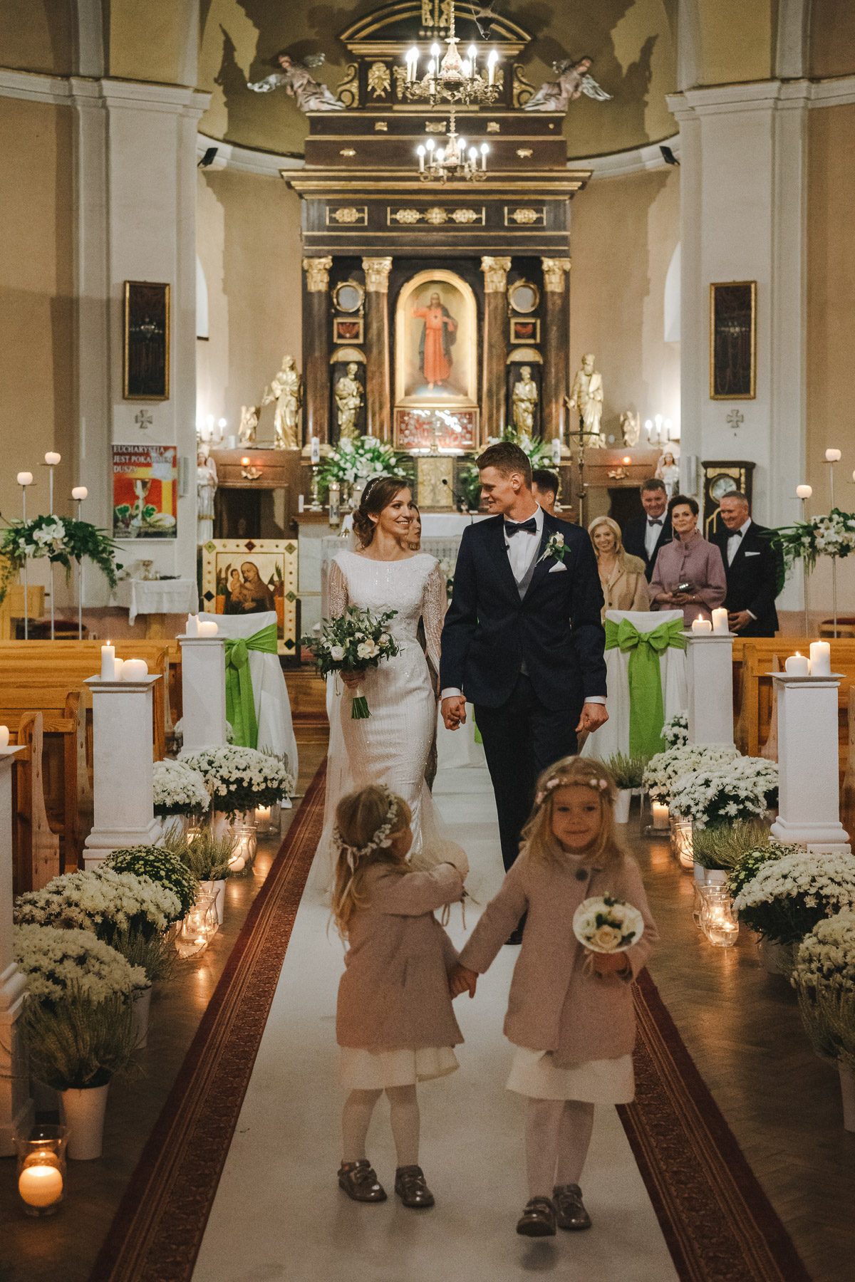 Uśmiechnięci nowożeńcy wychodzą z kościoła po zakończonej ceremonii zaślubin.
