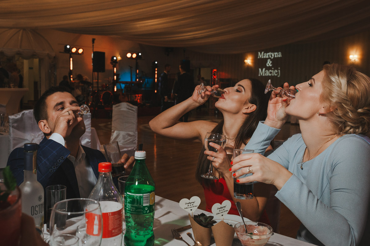 Goście weselni przy stole piją alkohol w Hotelu Maxim Stawiszyn.
