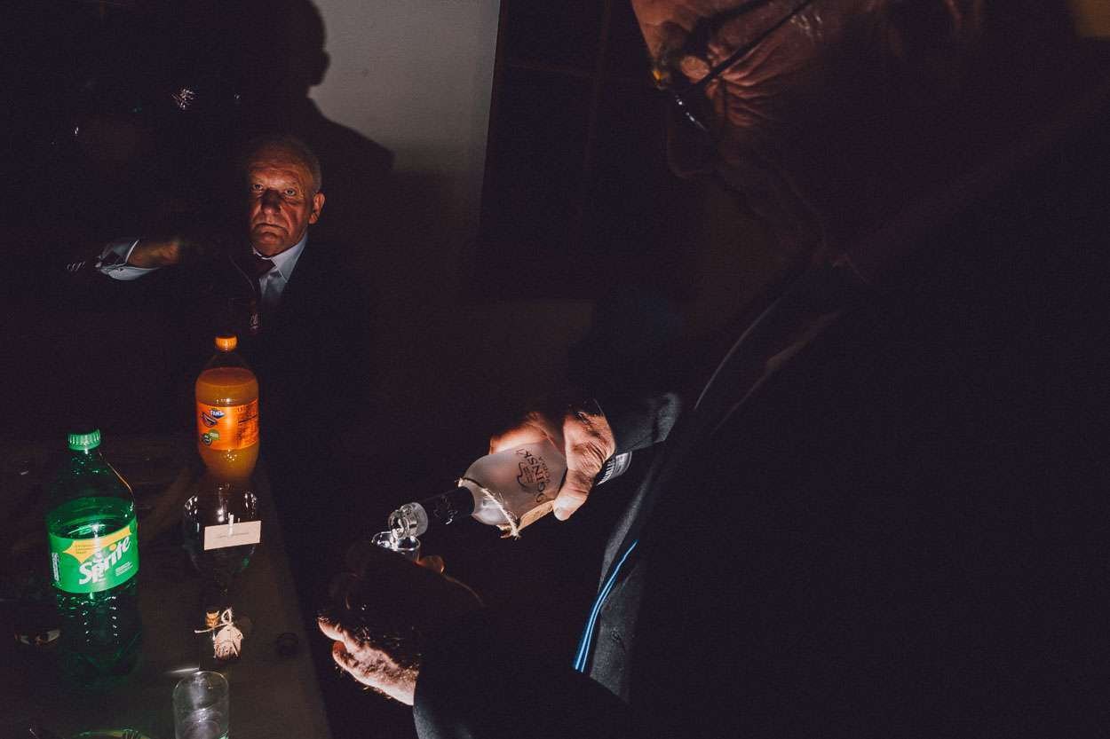 Mężczyzna nalewa alkohol do kieliszka podczas przyjęcia weselnego w Chacie Baranowskiej.