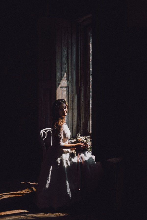 Pałac Krowiarki sesja ślubna - Pani młoda siedzi przy oknie na krześle i trzyma w ręce bukiet kwiatów