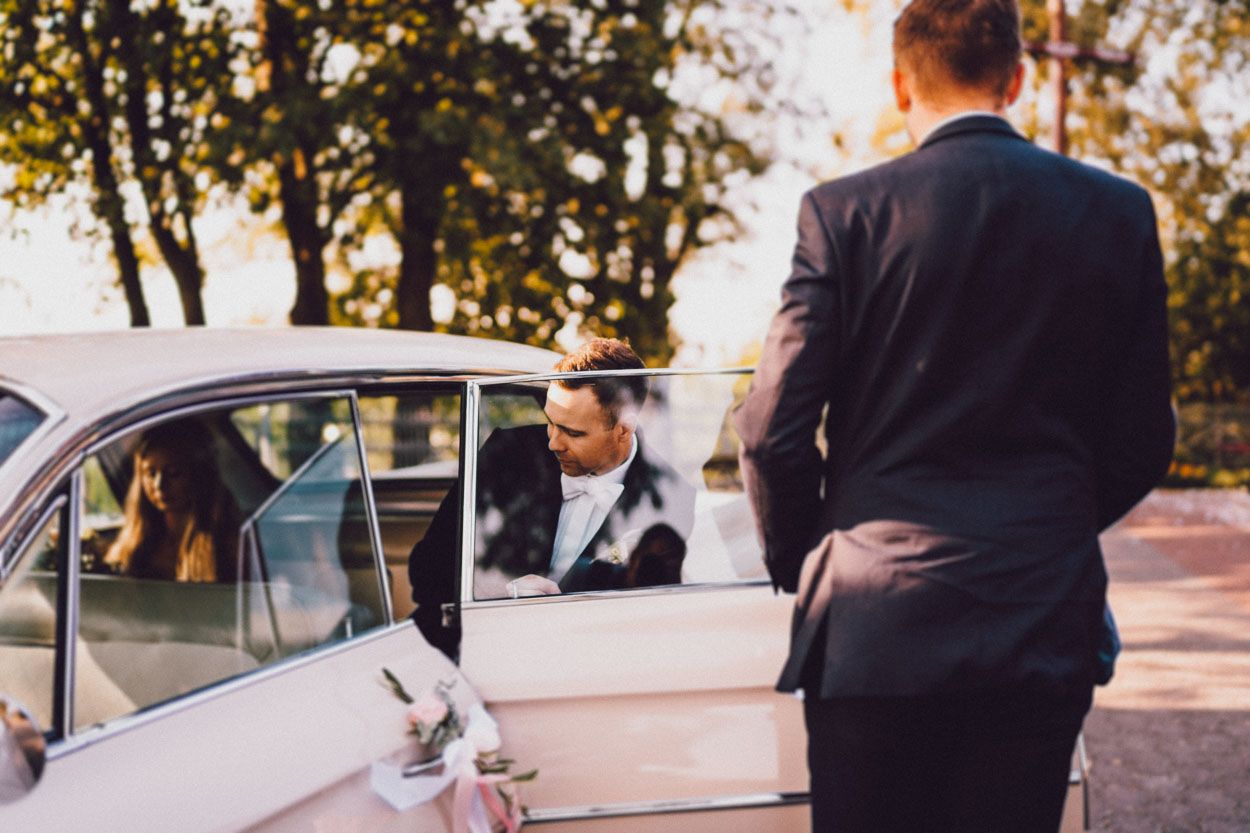 Pan młody wsiada do samochodu po ceremonii zaślubin
