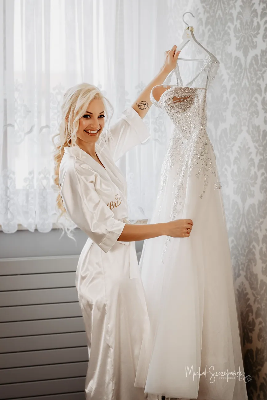 Panna Młoda przed weselem w Topolova Banqueting Halls trzyma suknie ślubną